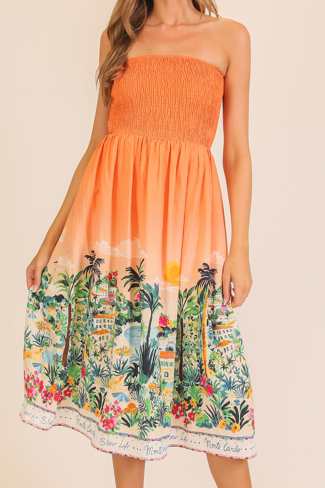 Orange strapless dress with tropical print on a beige background